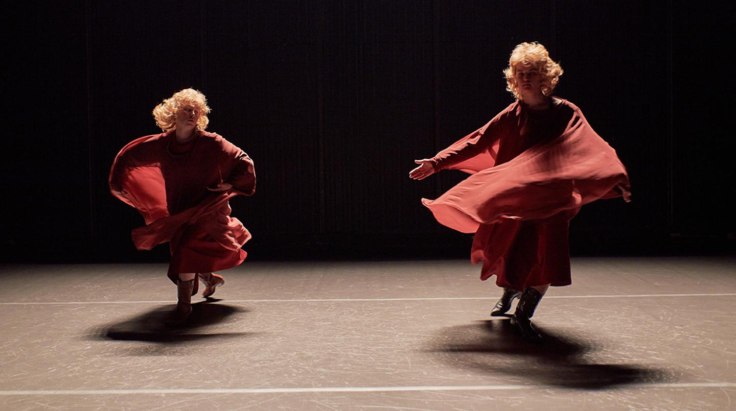 Två dansande personer som snurrar i röda tyger. Från föreställningen The New Theatre/Scenex 2022.