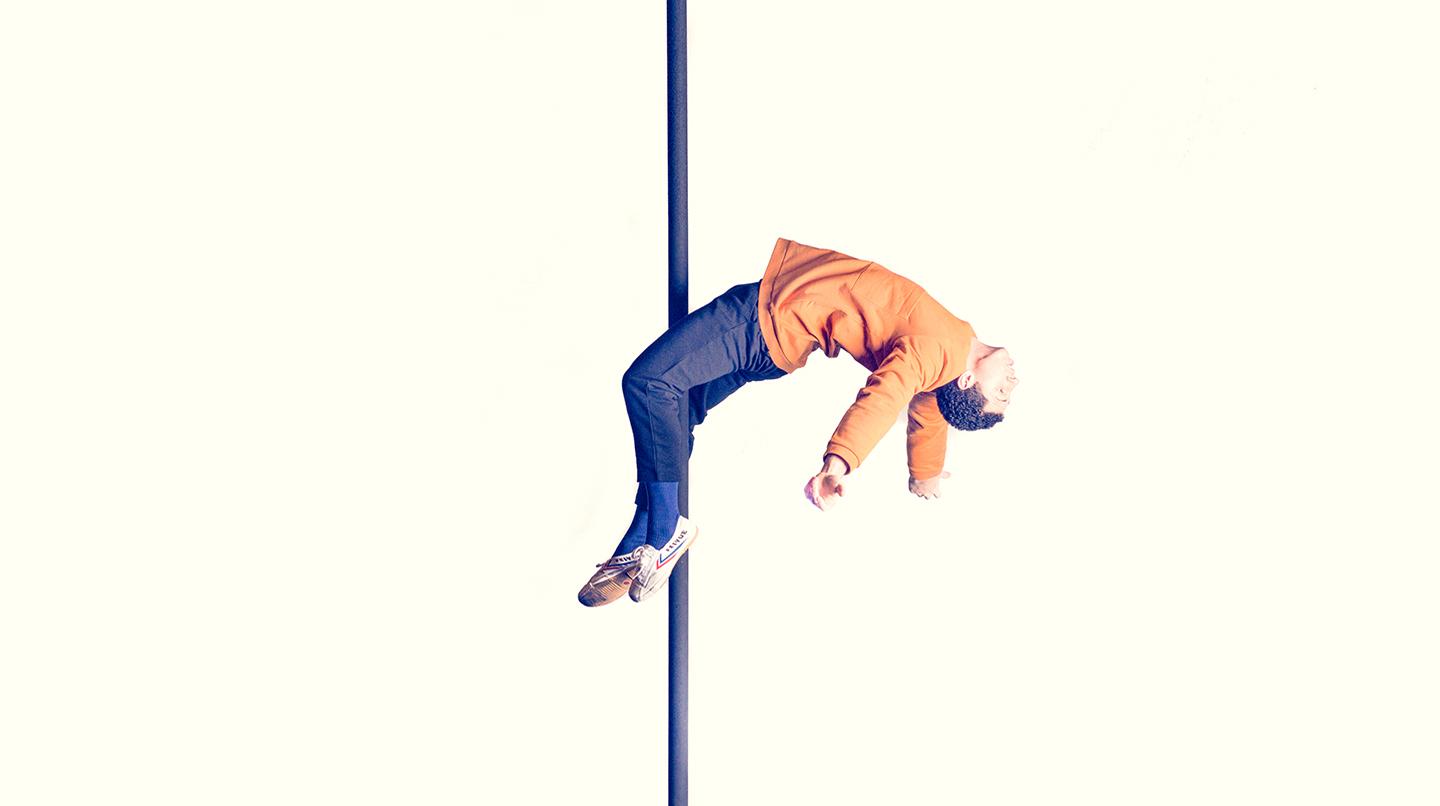 En cirkusstudent med benen om en kinesisk påle, hängandes bakåt i brygga. Från examensföreställningen Closing Acts, 2018.