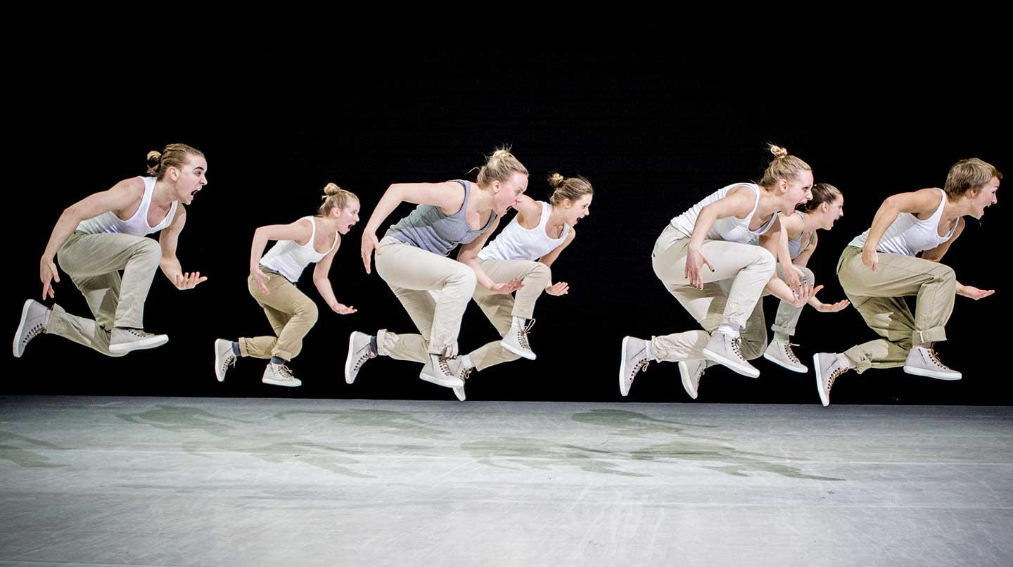 Sju kvinnliga dansare som hoppar över en scen.