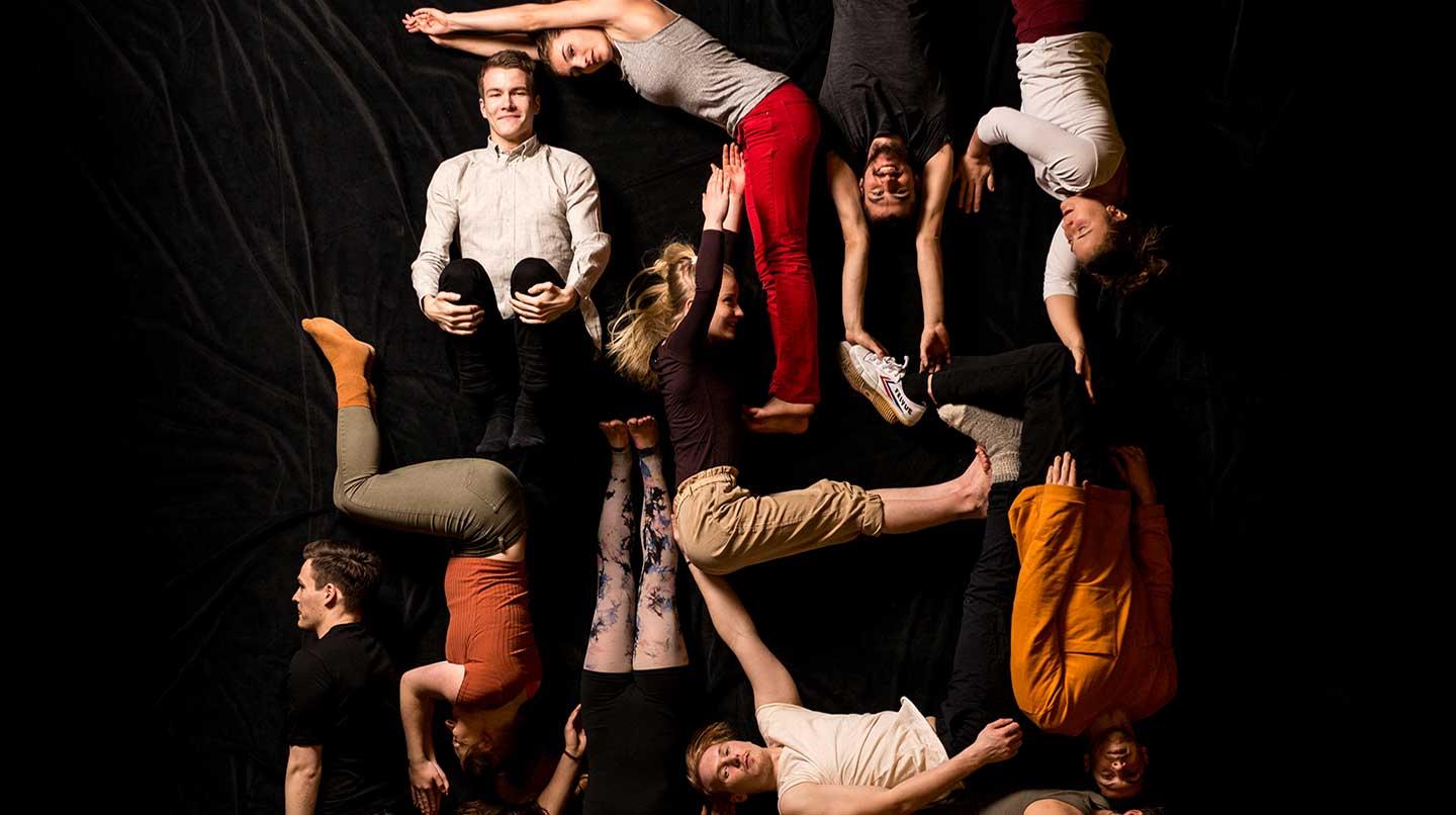 Ett tiotal unga människor ligger på ett svart golv i olika akrobatiska positioner