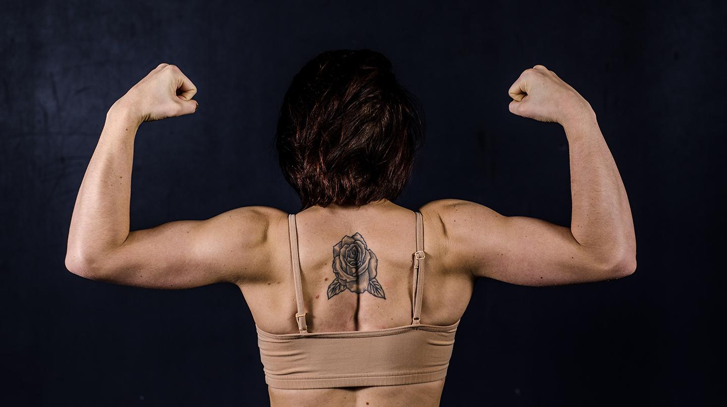 En kvinnlig ryggtavla med armar som spänner sina biceps. 